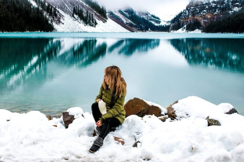 カナダアルバータ州の湖の前にすわる女性